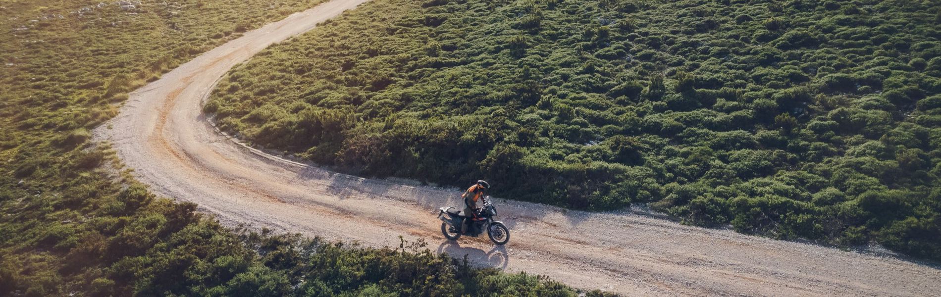 Aerial view of a rider on an adventure bike on a winding dirt road